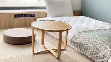 A modern bedroom with a bed, a small round table, and a bench.