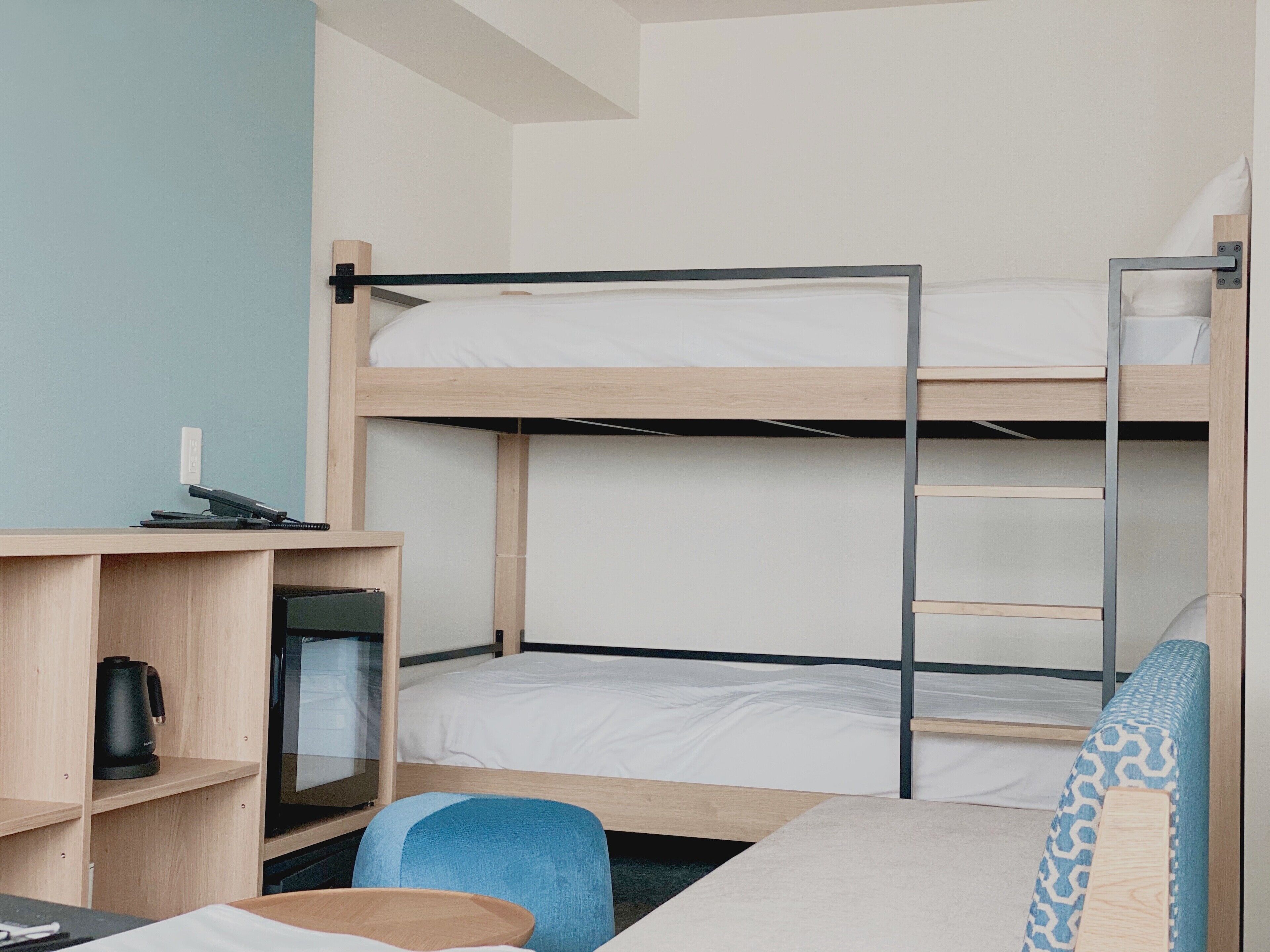 Une chambre avec un lit superposé, un bureau, une chaise et une petite table.
