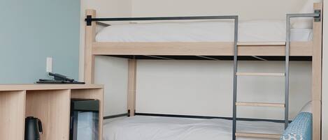 Une chambre avec un lit superposé, un bureau, une chaise et une petite table.