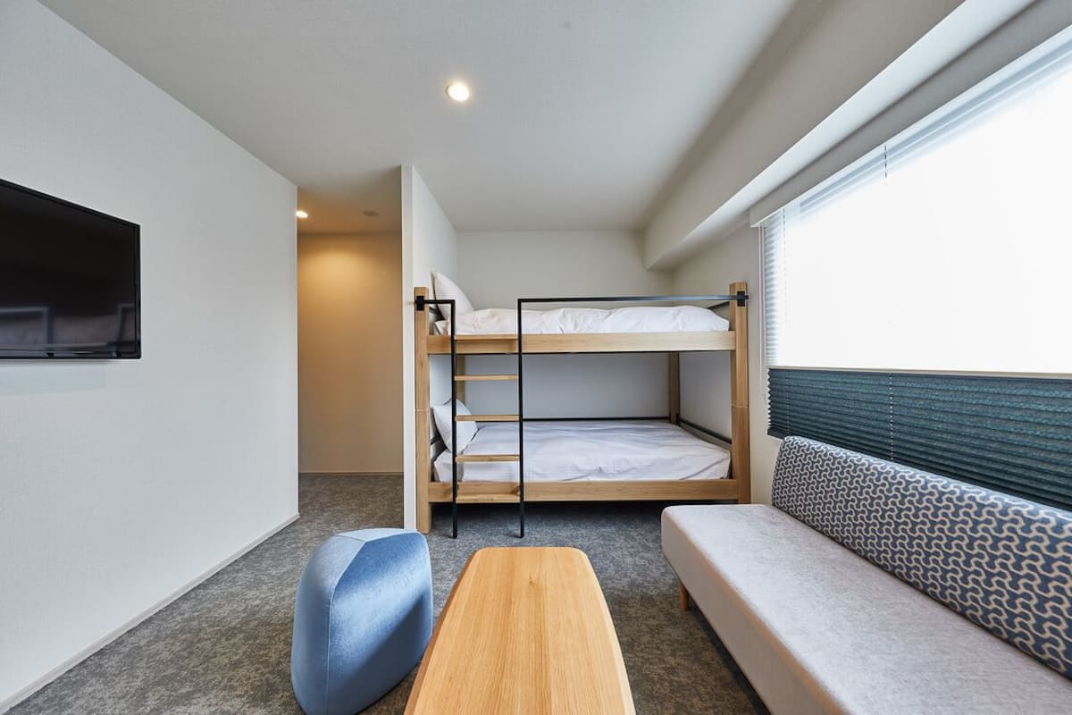 A bunk bed room with a sofa and a small table.