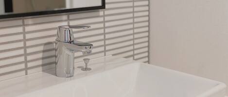 A white bathroom sink with a chrome faucet and a mirror above it.