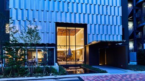 Un hotel moderno con un exterior único, destacando una fachada con diseño y una entrada bien iluminada.