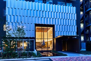 Un hotel moderno con un exterior único, destacando una fachada con diseño y una entrada bien iluminada.