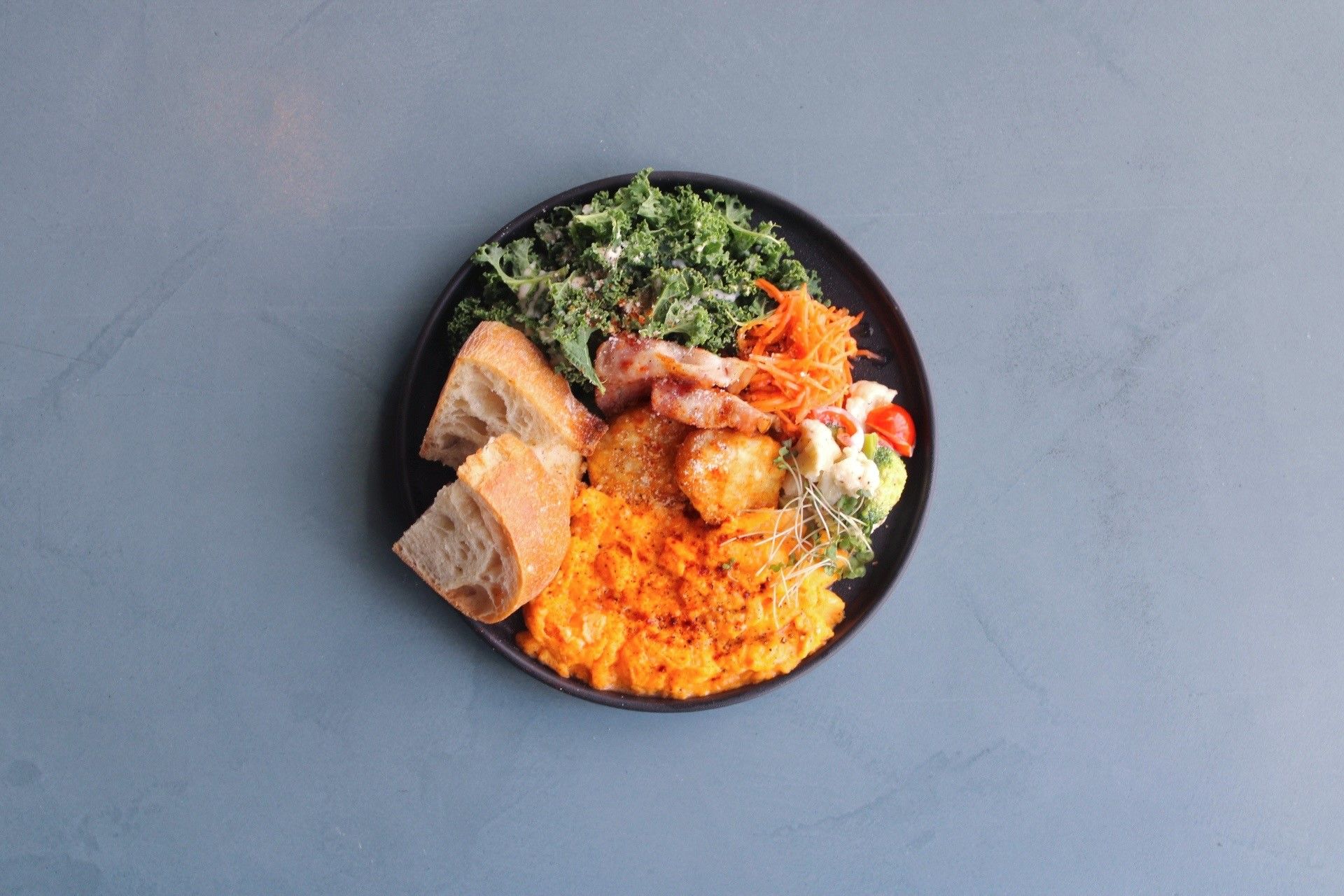 A plate with various food items including bread, a meat dish, and vegetables.