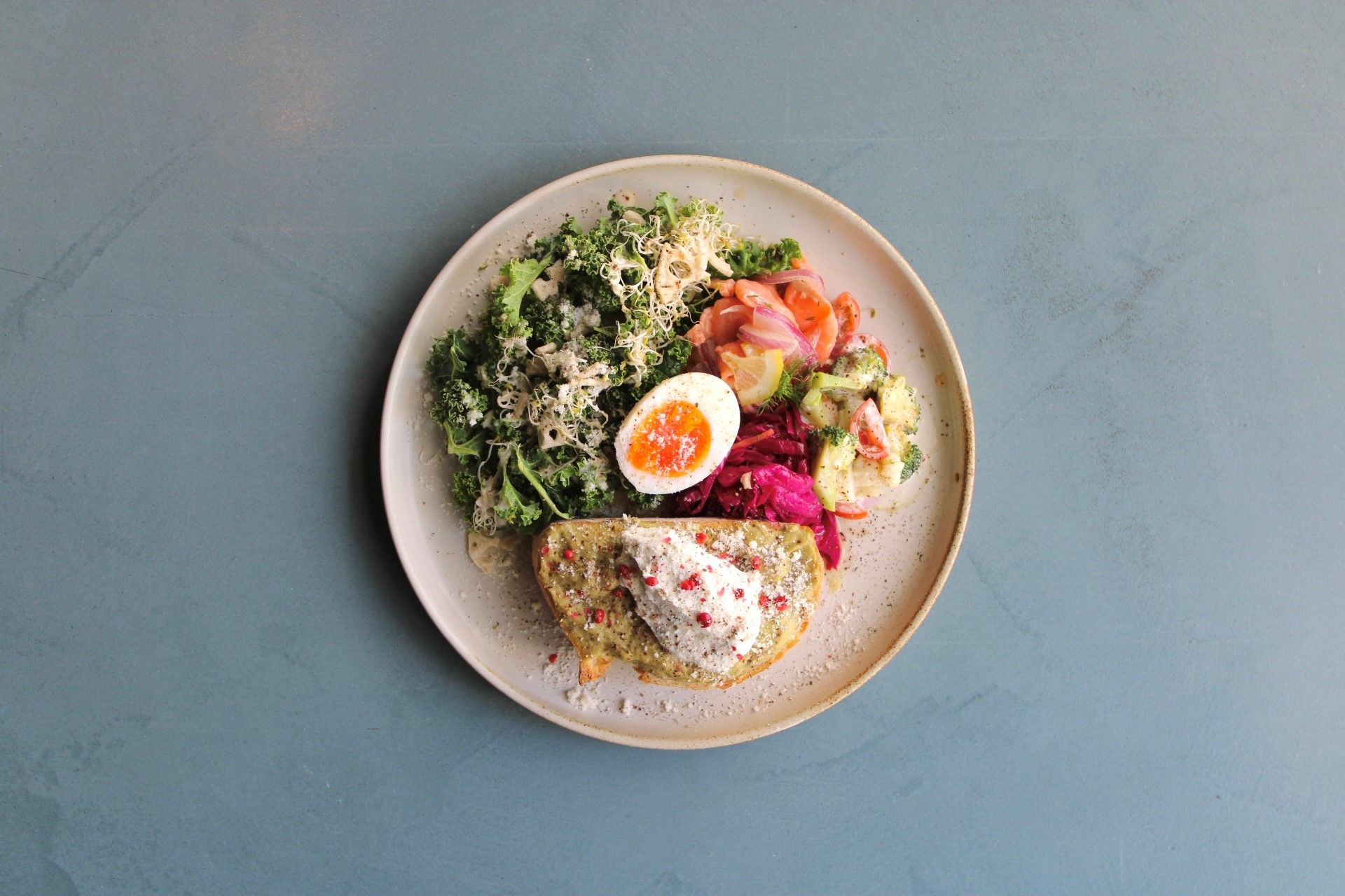 A plate with a variety of foods including a piece of fish, a boiled egg, and mixed vegetables.