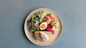 A plate with a variety of foods including a piece of fish, a boiled egg, and mixed vegetables.