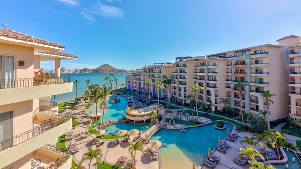 A resort with multiple buildings, a central pool area, and a view of the ocean.