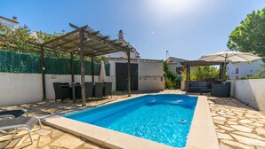 Ein Schwimmbad mit Pergola, Liegestühlen und einer Steinterrasse.