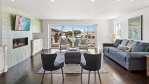 A spacious living room with a fireplace, a large TV, and a view of the marina through large windows.