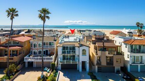 A coastal residential area with modern houses, a clear blue sky, and a beach in the background.