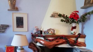 A cozy living room with a fireplace, a stone wall, a red rug, and a lamp. - L'Agrifoglio (Aritzo)