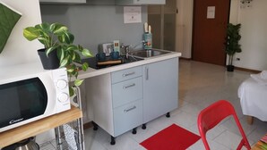 Een kleine keuken met een magnetron, spoelbak en kastjes.