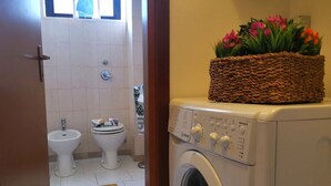 Een wasruimte met een wasmachine, een bidet en een toilet.