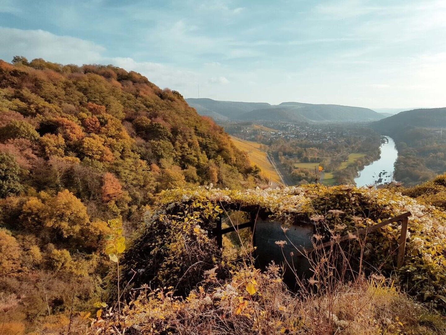 Een uitzicht over een vallei met een rivier, omringd door heuvels en herfstkleuren.