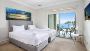 A hotel room with two beds, a balcony with a view of the sea, and a painting on the wall. - Unit 24 - 3 Bed Ocean View (TERRIGAL)