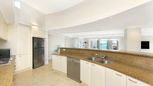Eine moderne Küche mit weißen Schränken, einem Edelstahlkühlschrank, einer Spülmaschine und einer Arbeitsplatte aus Granit.