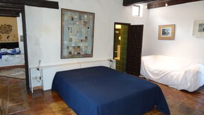 Una habitación con una cama, un cuadro y una puerta con marco verde.