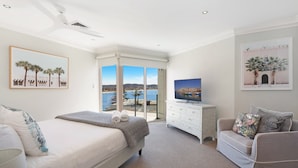 Quarto com cama, televisão em uma cômoda e vista para o mar por uma porta deslizante.