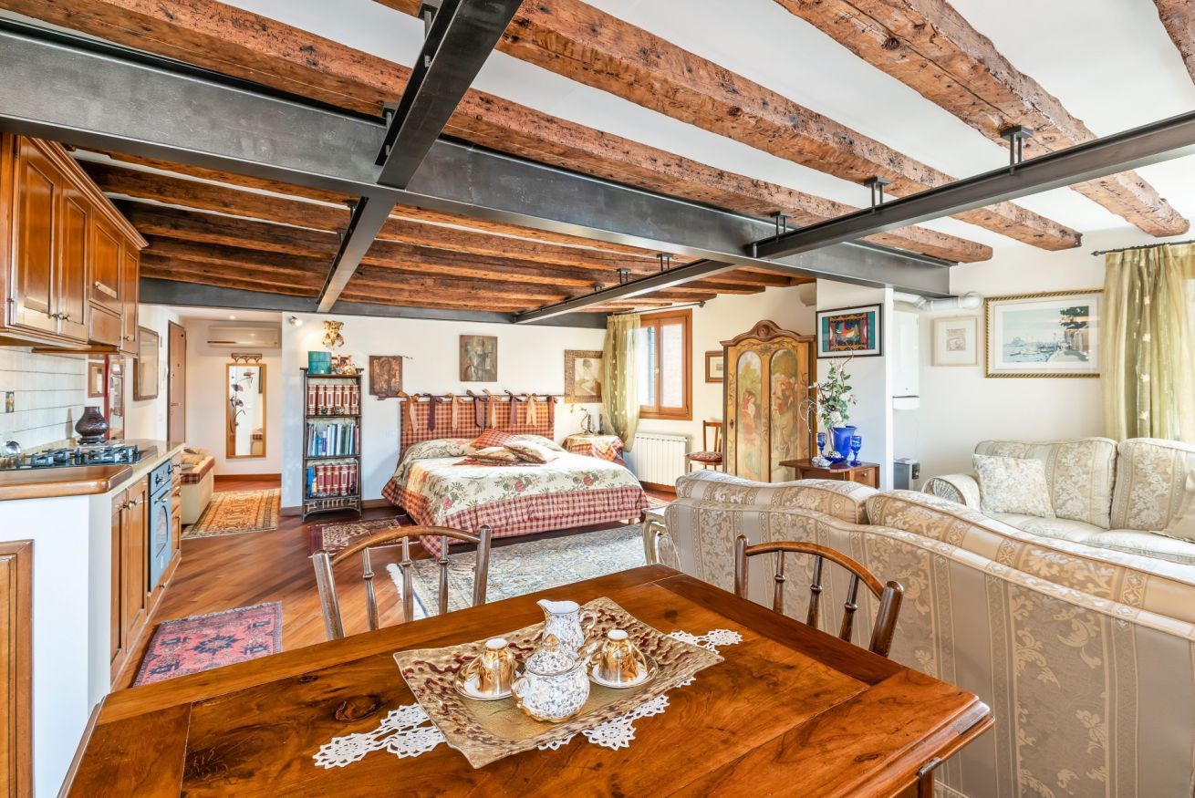 Un espacio habitable amplio con techo de madera, una mesa de comedor con mantel de encaje y un sofá.