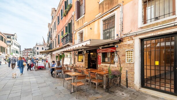A street with outdoor seating, a café, and buildings with balconies. - GuestHost - Exclusive studio perfect for 2 people and furnished in typical Venetian style overlooking the Canareggio Canal and Palazzo Labia. Location is strategic and convenient for those arriving in Venice: about 5 minutes walk from the train station a (Venezia)