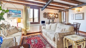 A living room with a sofa, a coffee table, a patterned rug, and a dining area with chairs. - GuestHost - Exclusive studio perfect for 2 people and furnished in typical Venetian style overlooking the Canareggio Canal and Palazzo Labia. Location is strategic and convenient for those arriving in Venice: about 5 minutes walk from the train station a (Venezia)
