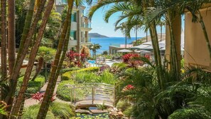 A resort with a pool, palm trees, and a view of the ocean. - Unit 22 - 3 Bed Ocean View (TERRIGAL)