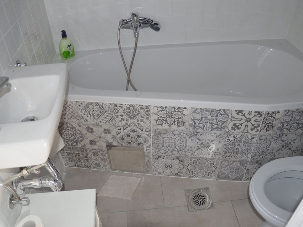 Ein Badezimmer mit Badewanne, Waschbecken, Toilette und gemusterten Fliesen.