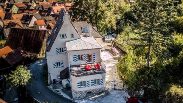 A two-story building with a balcony, surrounded by trees and a village. - VILLA in VELDEN (Velden)