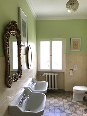 A bathroom with two sinks, a toilet, a radiator, and a window with a door. - VILLA in VELDEN (Velden)