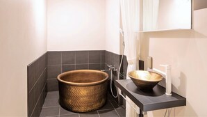 Une salle de bain moderne avec une baignoire en bois, un lavabo sur colonne et une douche.