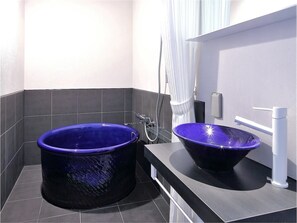 Een badkamer met een groot blauw bad en een bijpassende wastafel, beide met moderne voorzieningen.