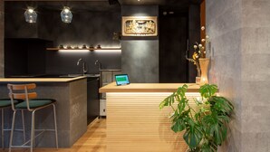 Une cuisine moderne avec un îlot central en bois, des tabourets de bar et une tablette posée sur le comptoir.