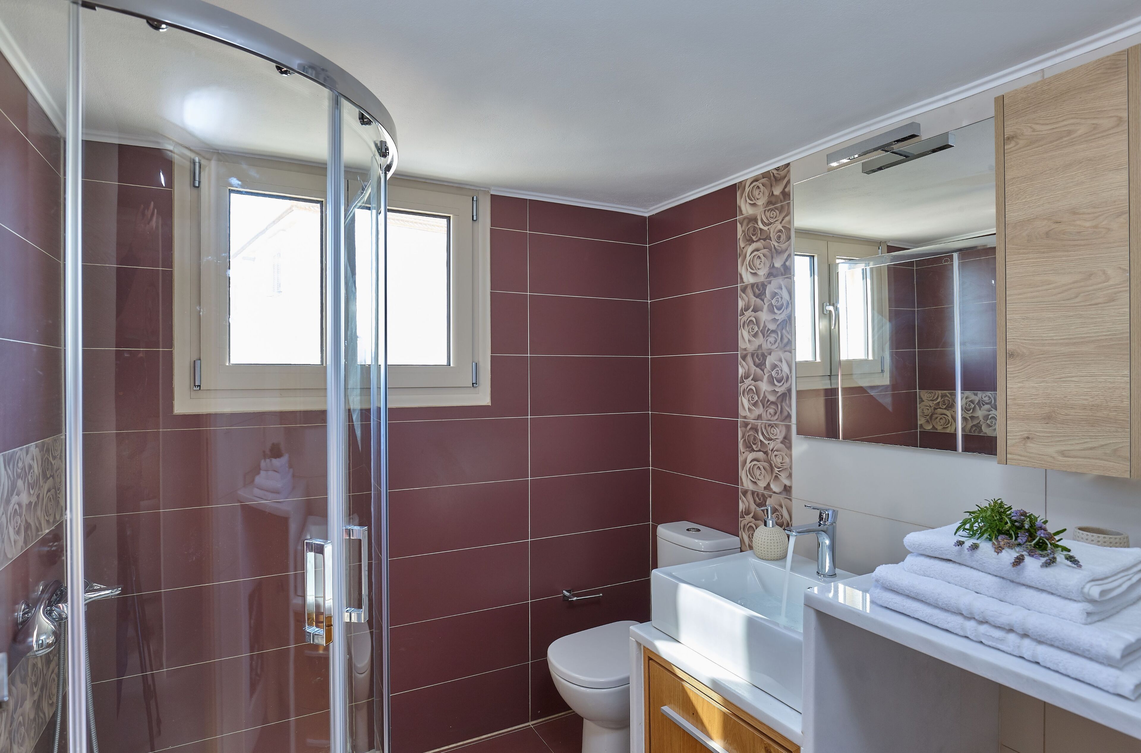 Ein modernes Badezimmer mit einer Duschkabine aus Glas, einer weißen Toilette und einem Waschtisch mit Spiegel und Handtüchenturm.
