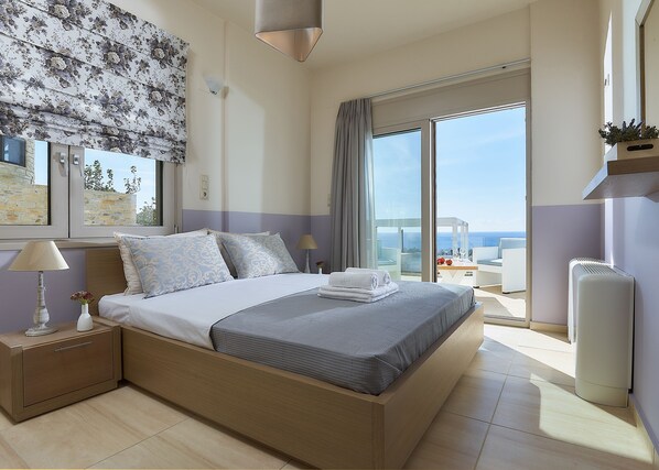 Une chambre à coucher comprenant un lit, des tables de chevet, une lampe, une fenêtre avec vue et un luminaire au plafond.