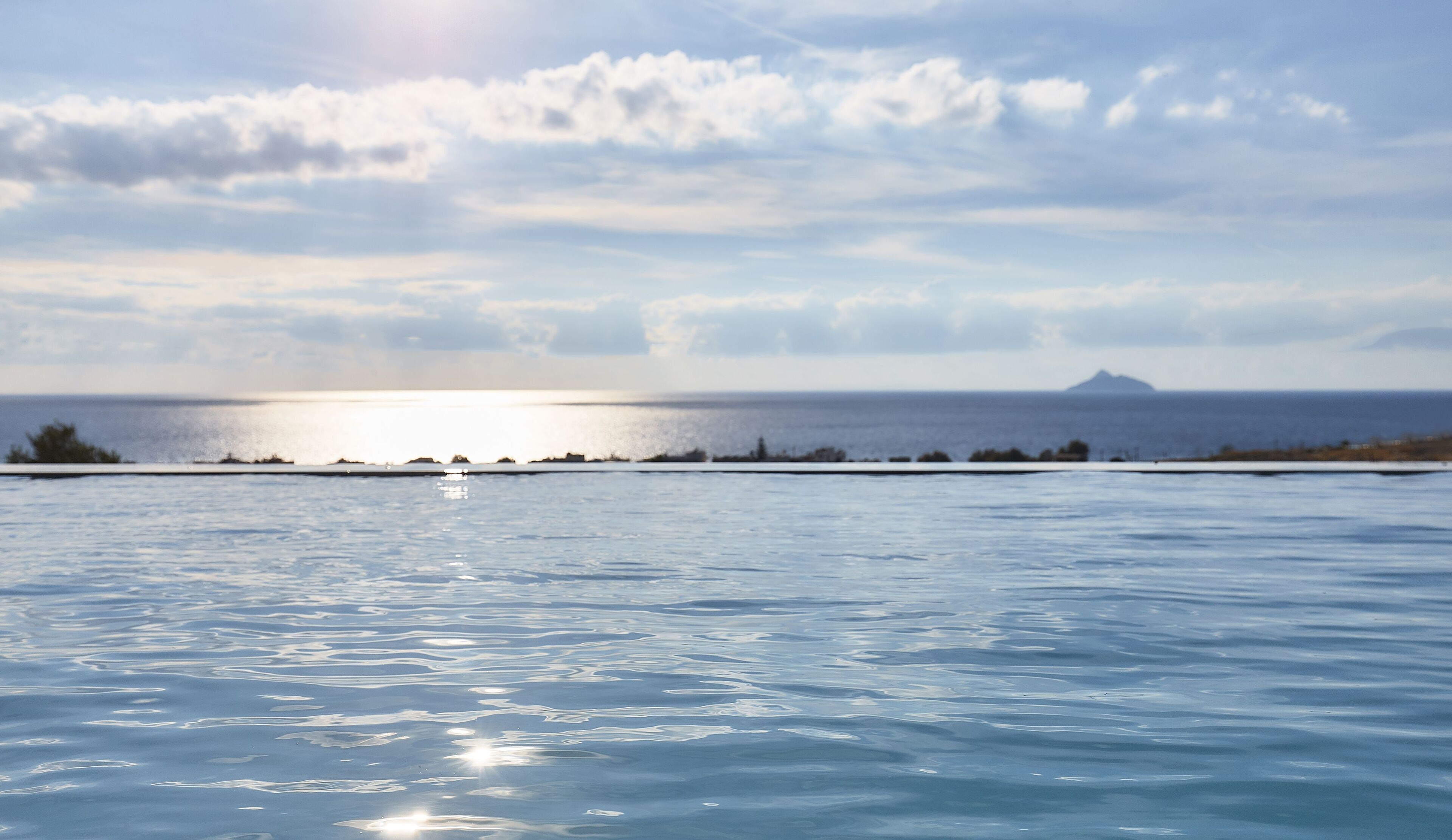 A calm sea with a clear sky and a distant mountain.