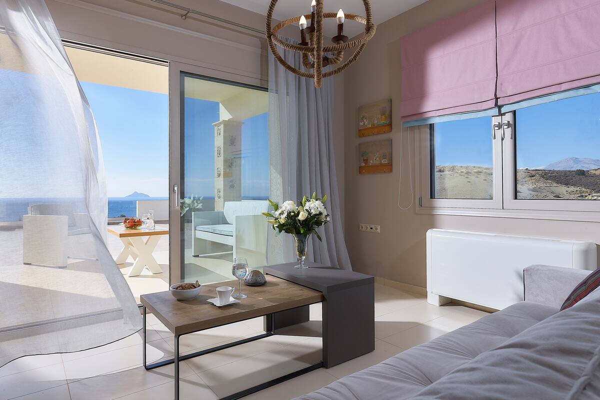 Ein modernes Wohnzimmer mit einer Couch, einem Couchtisch und Meerblick durch große Fenster.