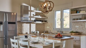A modern kitchen with a central island, stainless steel appliances, and a view of the outdoors. - Elkysti Crete (Faistos)