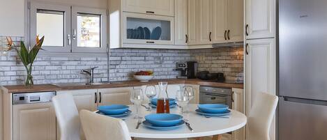 Una cocina moderna con armarios blancos, salpicadero de ladrillo y refrigerador de acero inoxidable.
