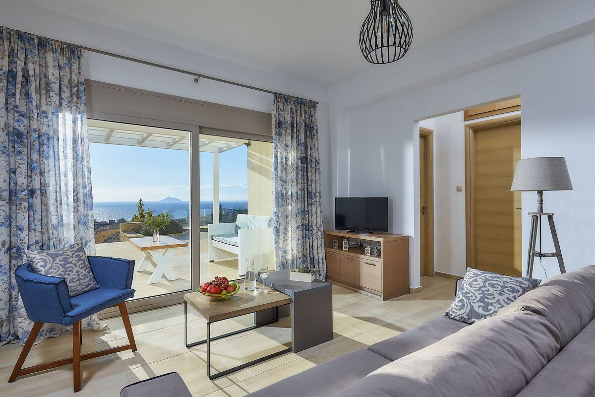 Ein modernes Wohnzimmer mit einer Couch, einem Sessel, einem Couchtisch, einem Fernseher und einer Lampe.