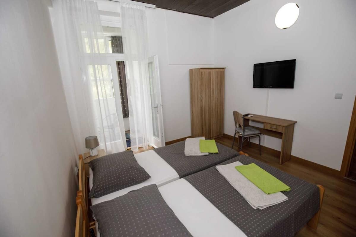 Un dormitorio con dos camas, un escritorio, una silla, un televisor y un armario.