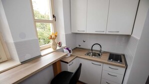 Cuina petita amb finestra, una aixeta i una cadira.