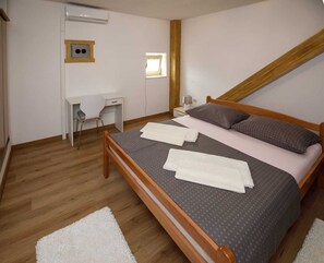 A bedroom with a wooden bed, a desk, a chair, and a small window. - Prenocite Kastel (Knin)