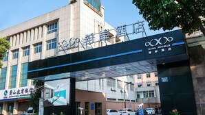 A hotel entrance with a large sign, a gated driveway, and several cars parked in front. - Xi'an Hotel Xiaoshan Airport Branch (Hangzhou)