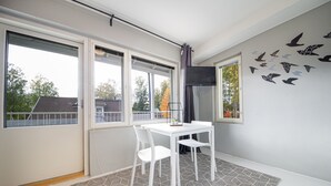 Une pièce moderne avec une table et des chaises blanches, de grandes fenêtres et un tapis à motifs géométriques.