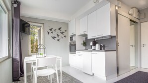 Une cuisine moderne avec des meubles blancs, une table à manger avec des chaises et un tapis à motifs.