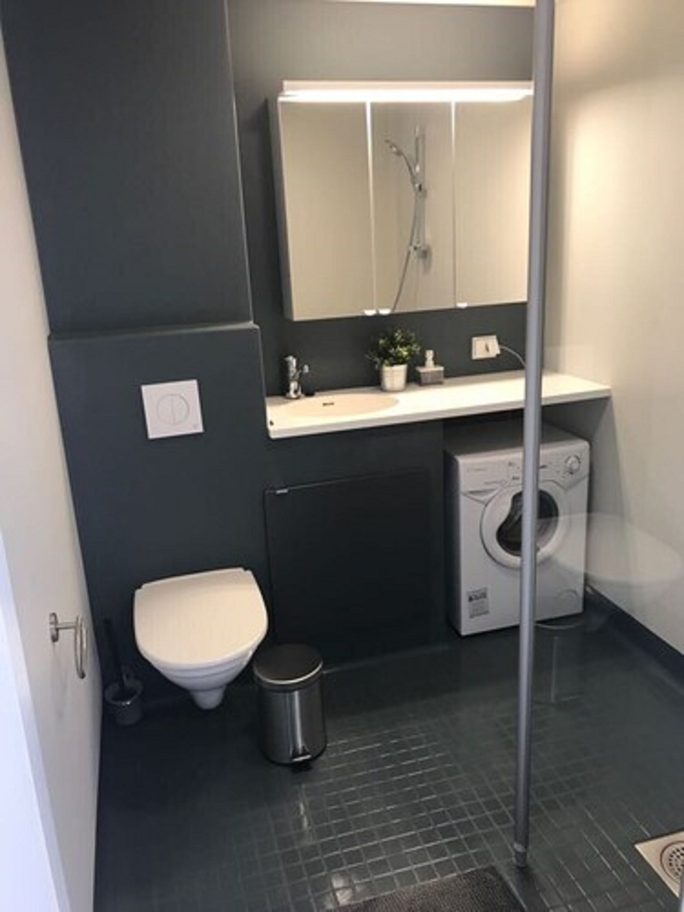 A compact bathroom with a toilet, sink, and washing machine.