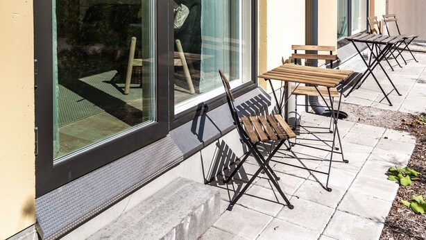 Patio esterno moderno con porte scorrevoli in vetro, pavimento in cemento e mobili in legno.