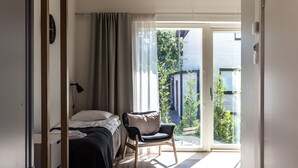 Una camera da letto con un letto, una sedia, una scrivania e una porta scorrevole che dà su un balcone.