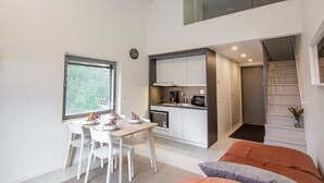 A modern kitchen with white cabinets, a dining area with white chairs, and a staircase leading to an upper level. - Spot Apartments Airport (Vantaa)