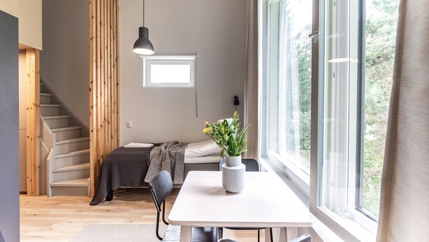 Un interno moderno con una scala, un letto, un'area pranzo e un'ampia finestra.